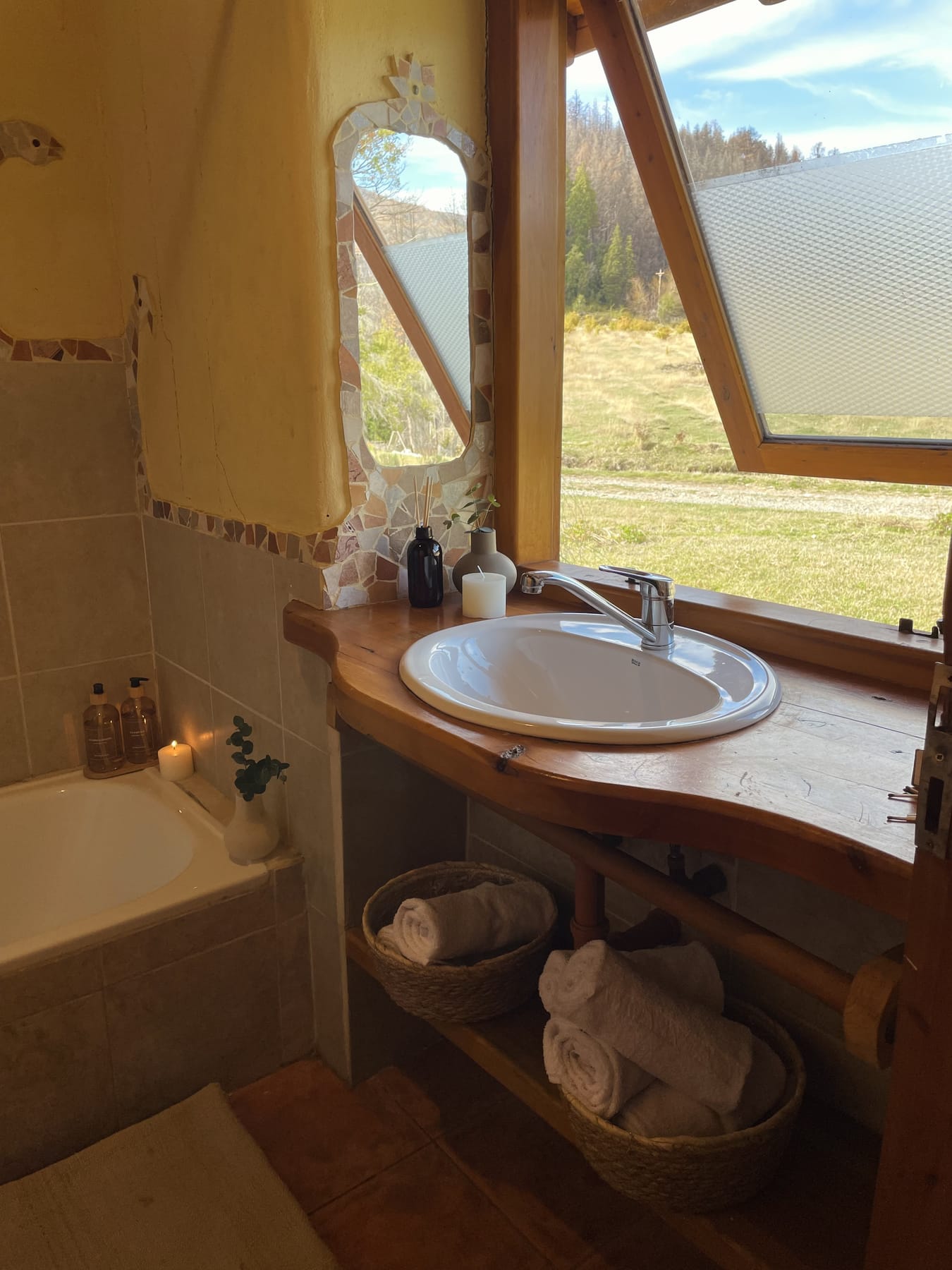 Baño con mosaicos, bañera y ventana hacia el bosque