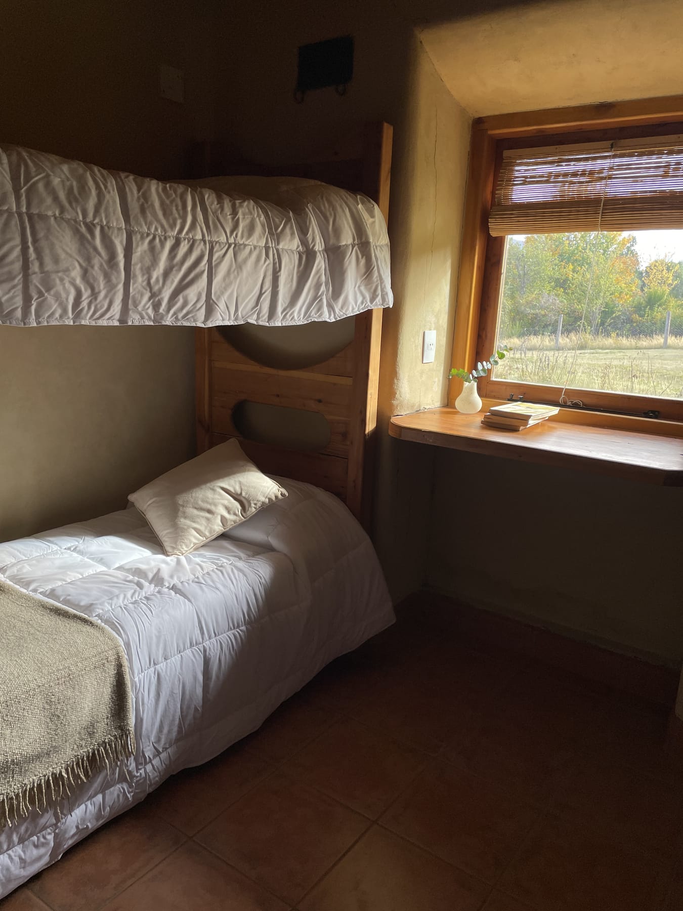 Habitación con cama, cucheta y ventana al campo